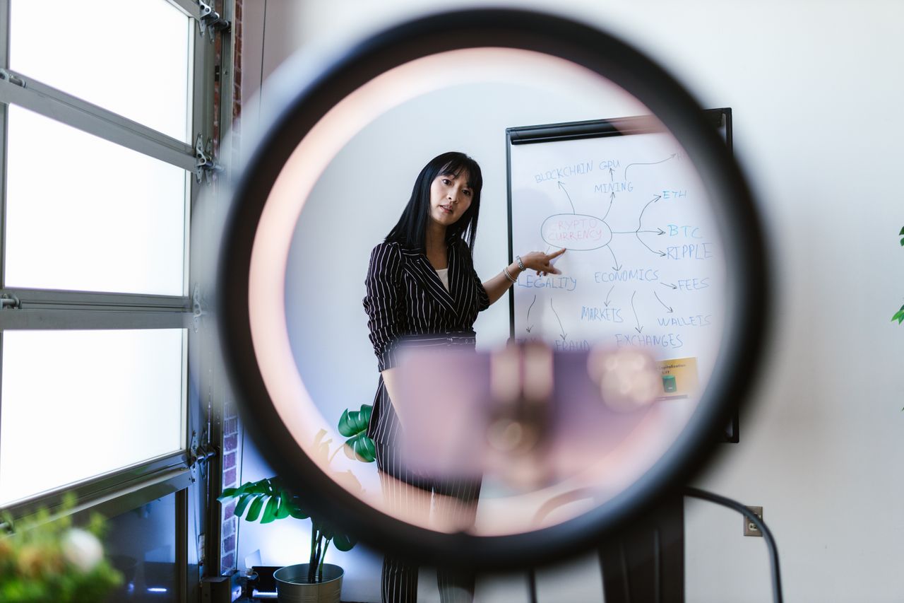 Services-02 A woman uses a ring light for an online presentation on economics and cryptocurrency.